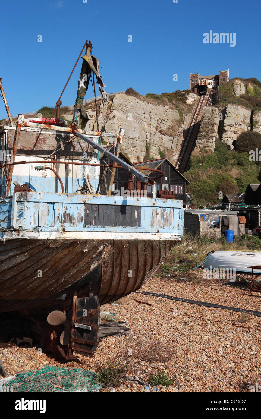 An old  wooden fishing boat with the funicular railway in the background on The Stade, Hastings, East Sussex, UK Stock Photo
