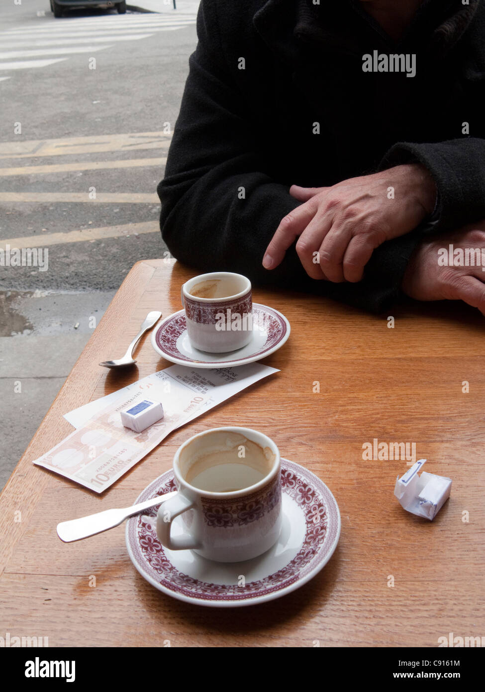 The typical Parisian street has small cafes with tables on the pavements where people sit and observe city life over small cups Stock Photo