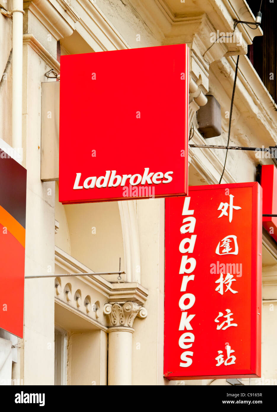 Sign outside a branch of Ladbrokes betting shop with Chinese text in the Chinatown area of central Manchester England UK Stock Photo