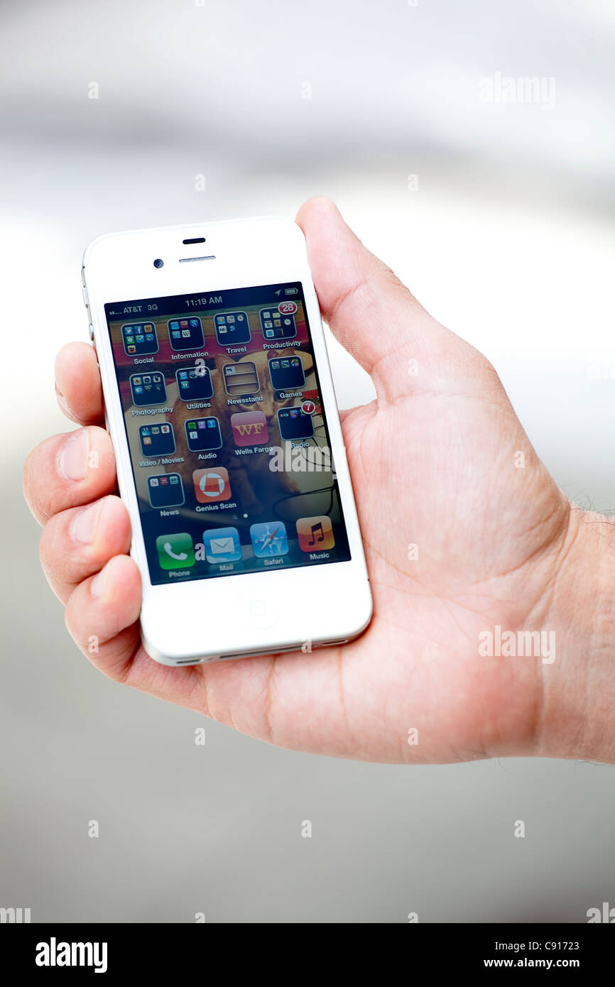 A white Apple Mac iPhone 4S being held to show the apps on it's home screen. Stock Photo