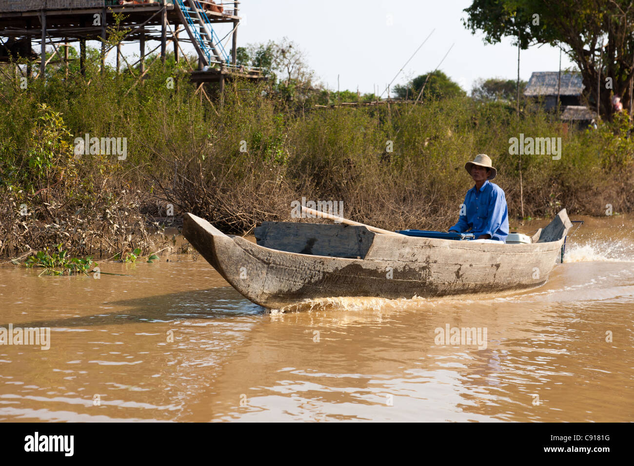 A local Cambodian man sitting in his boat on the river system of Tonle Sap Lake near Siem Reap. Stock Photo