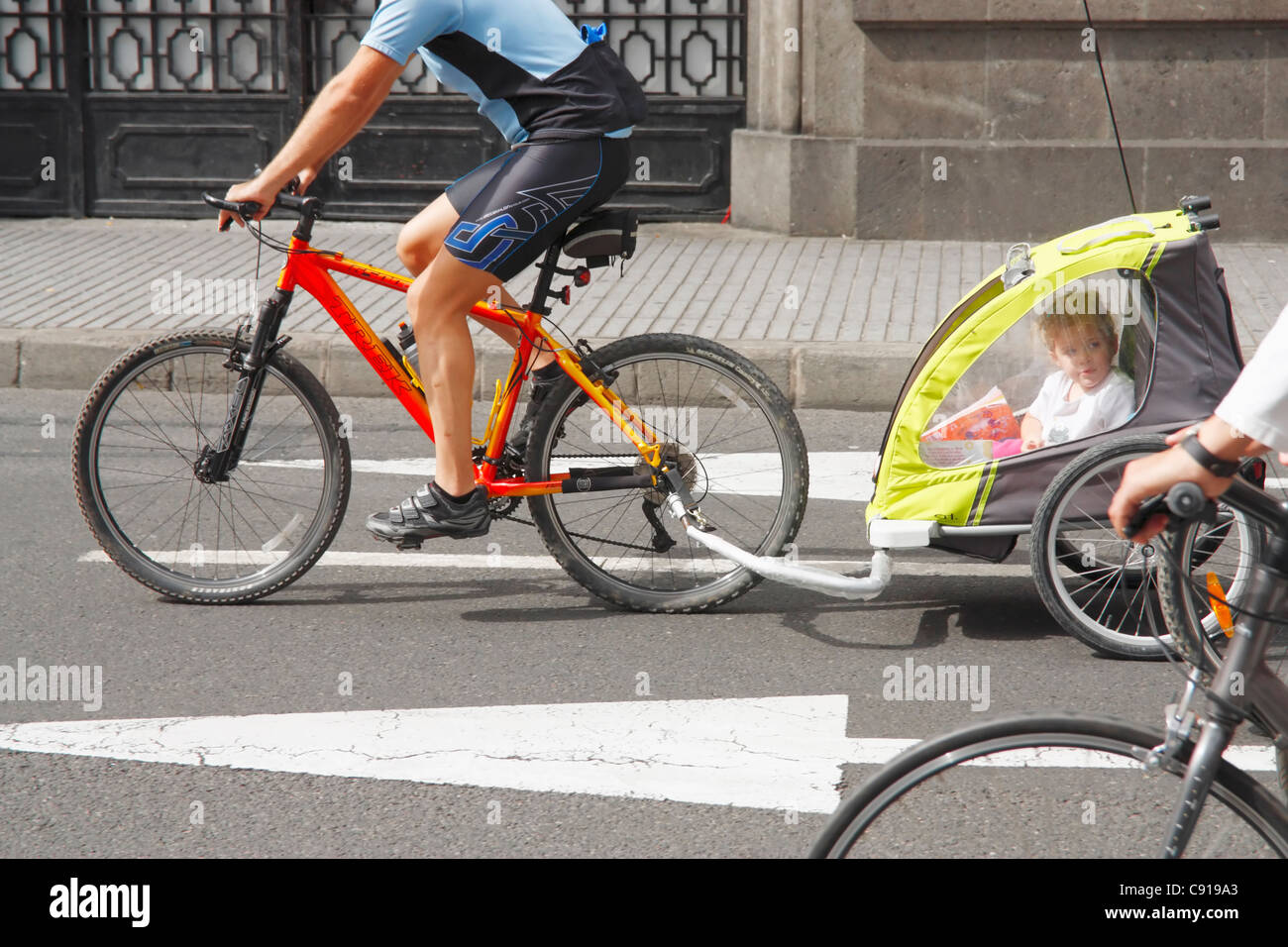 Man towing bike trailer with young child inside Stock Photo