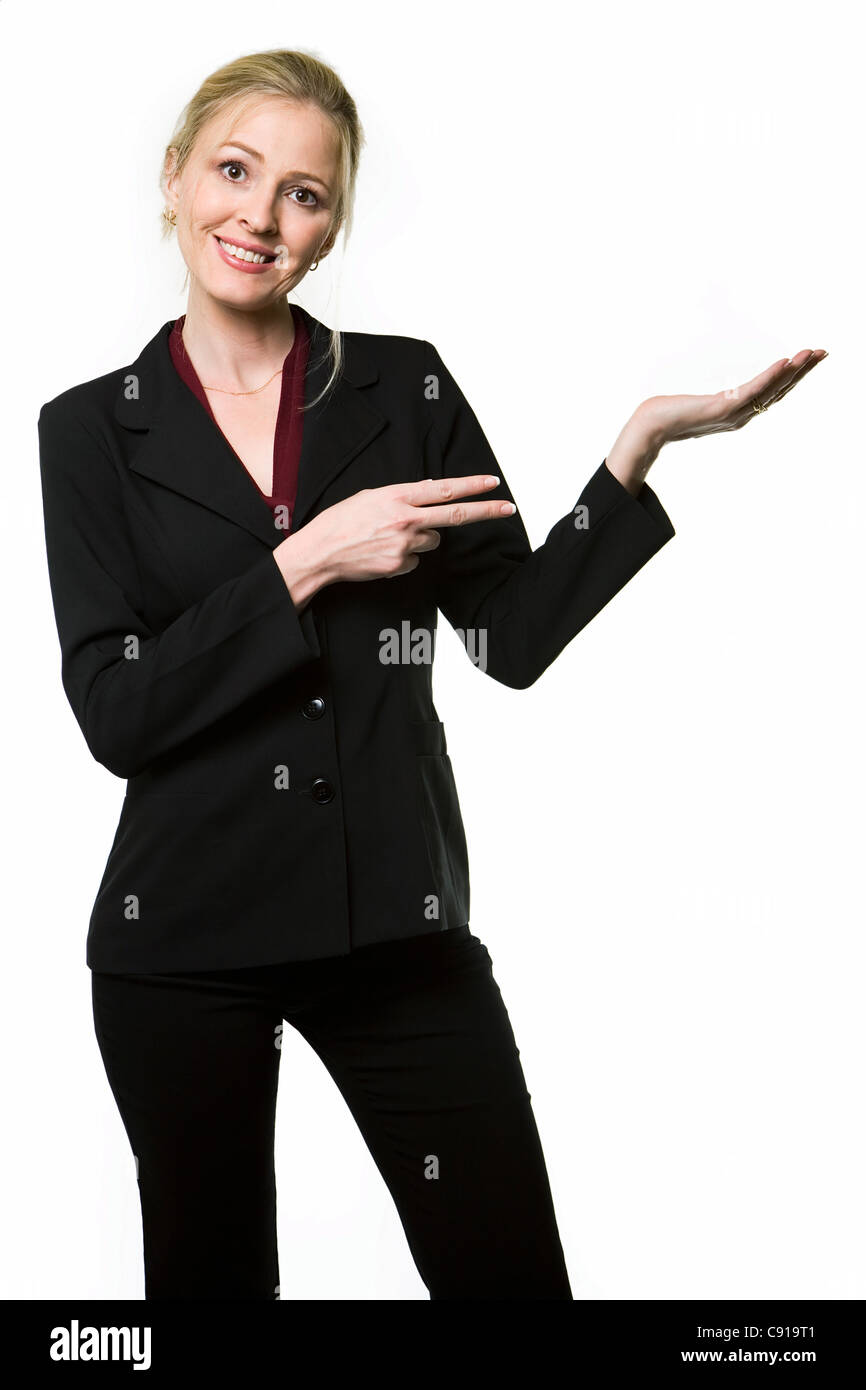 Attractive blond woman wearing a black business suit smiling holding up one hand and pointing at the empty hand with the other h Stock Photo