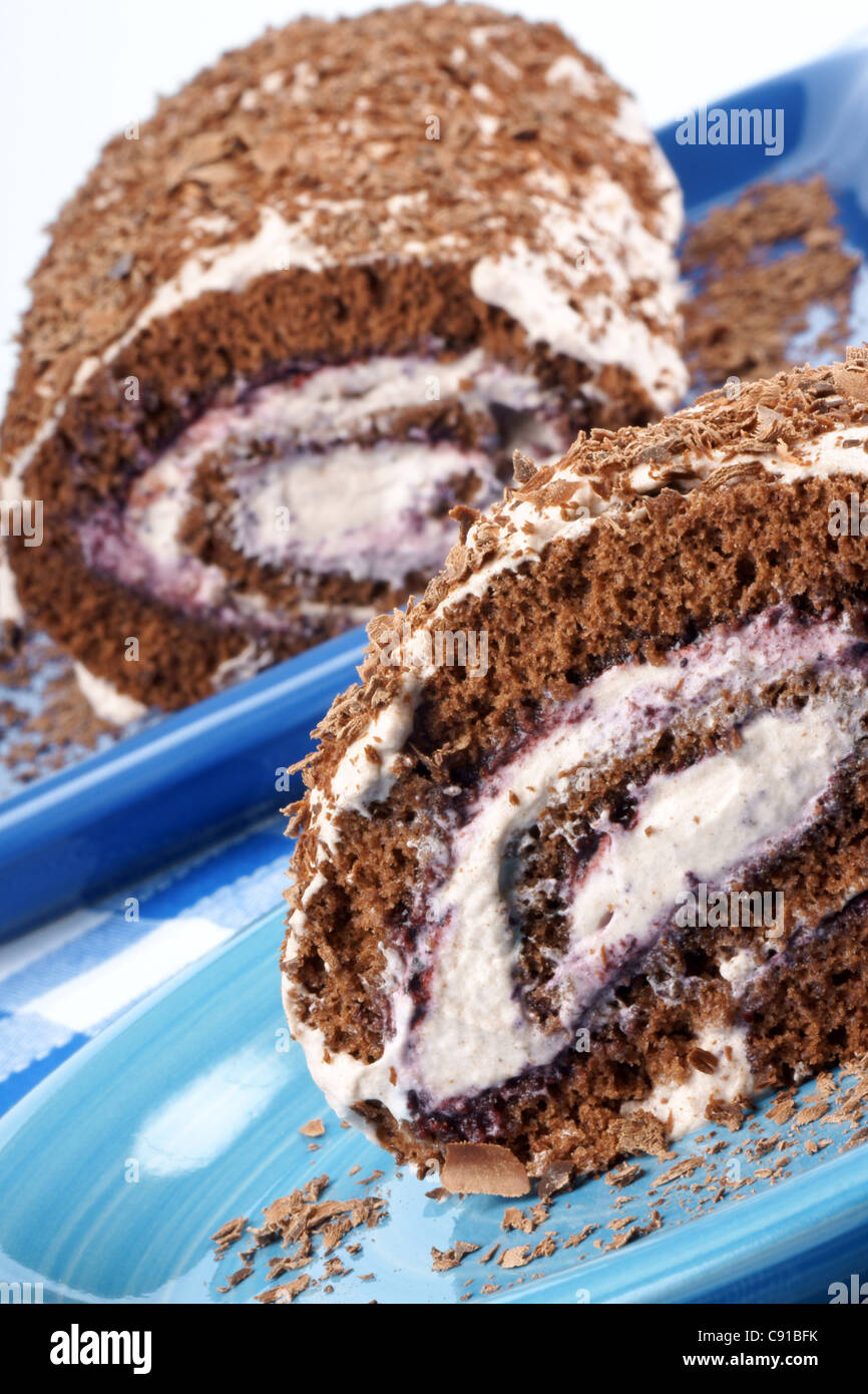 Chocolate swiss roll cake with berries jam and whipped cream over a ...