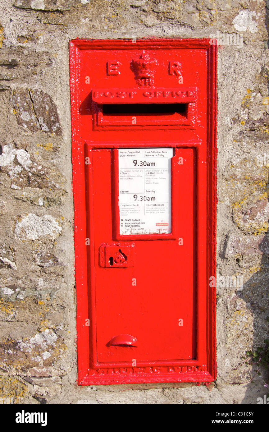Traditional red post box set in a stone wall outside of St Davids cathedral in Pembrokeshire. Stock Photo