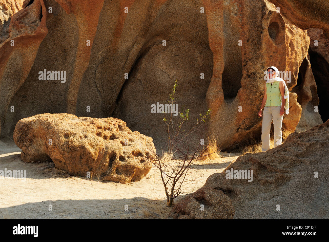 Woman walking through rock with bizarre eolian erosion, Namib desert, Namib, Namibia Stock Photo