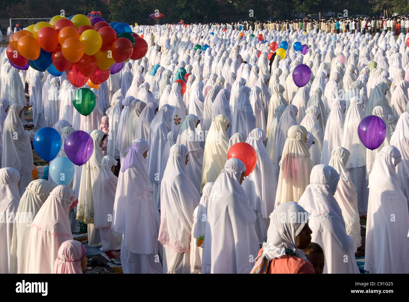 Women and girls standing wearing hijab muslim dress with balloons, Idul Fitri ceremony, Denpasar, Bali, Indonesia Stock Photo