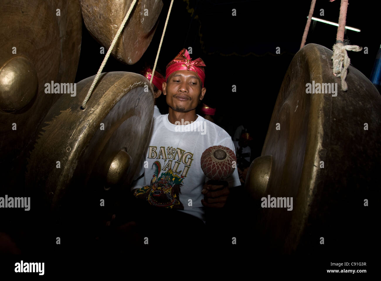 Gamelan musician playing gongs in circumcision ceremony, Randublatung