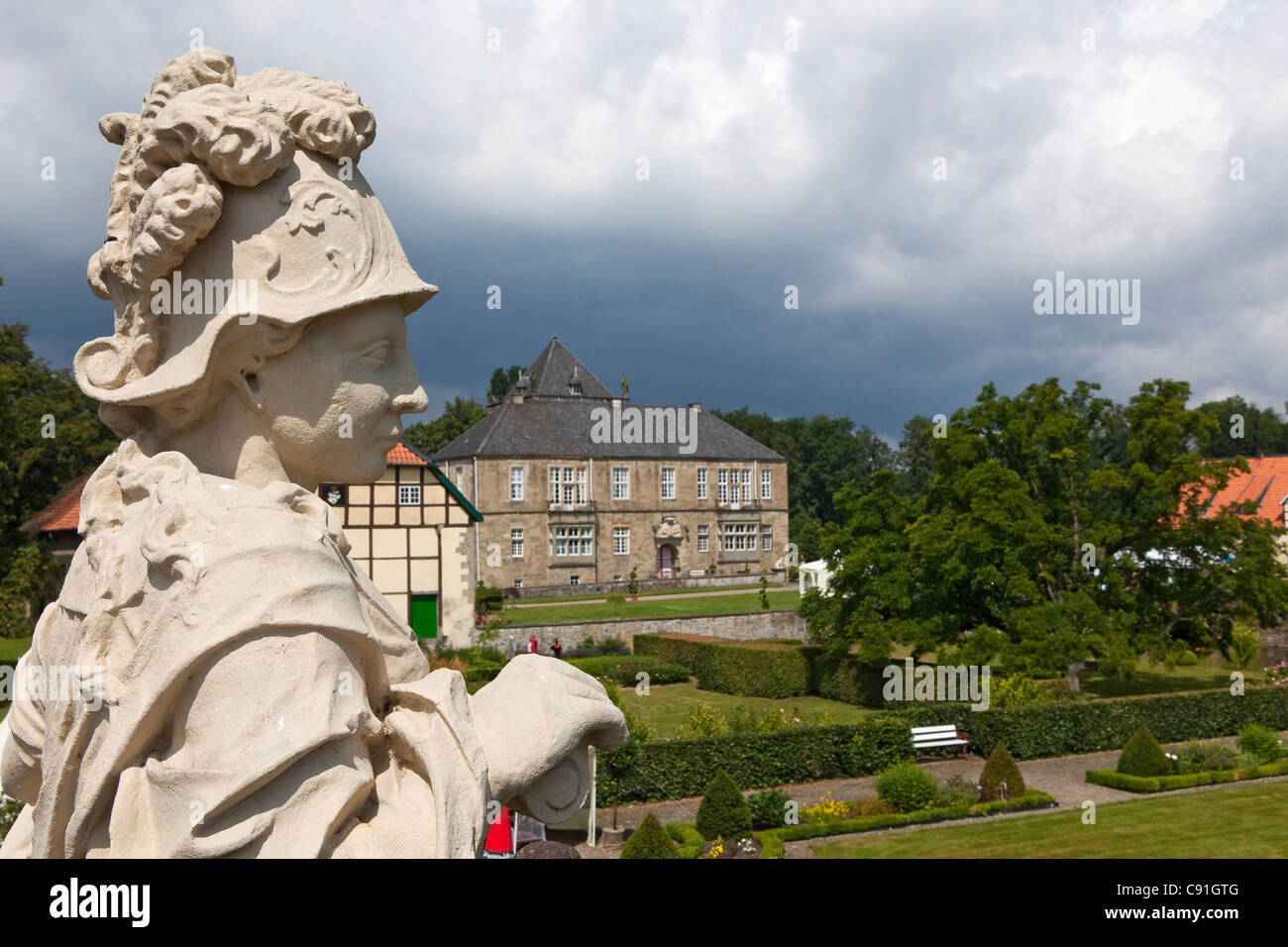 Gesmold castle and castle grounds, sculpture in the foreground, black clouds, Gesmold, Meller, Lower Saxony, Germany Stock Photo