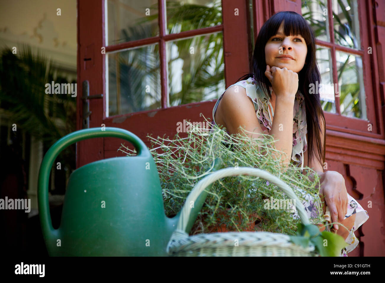 Woman sitting with plants on back porch Stock Photo - Alamy