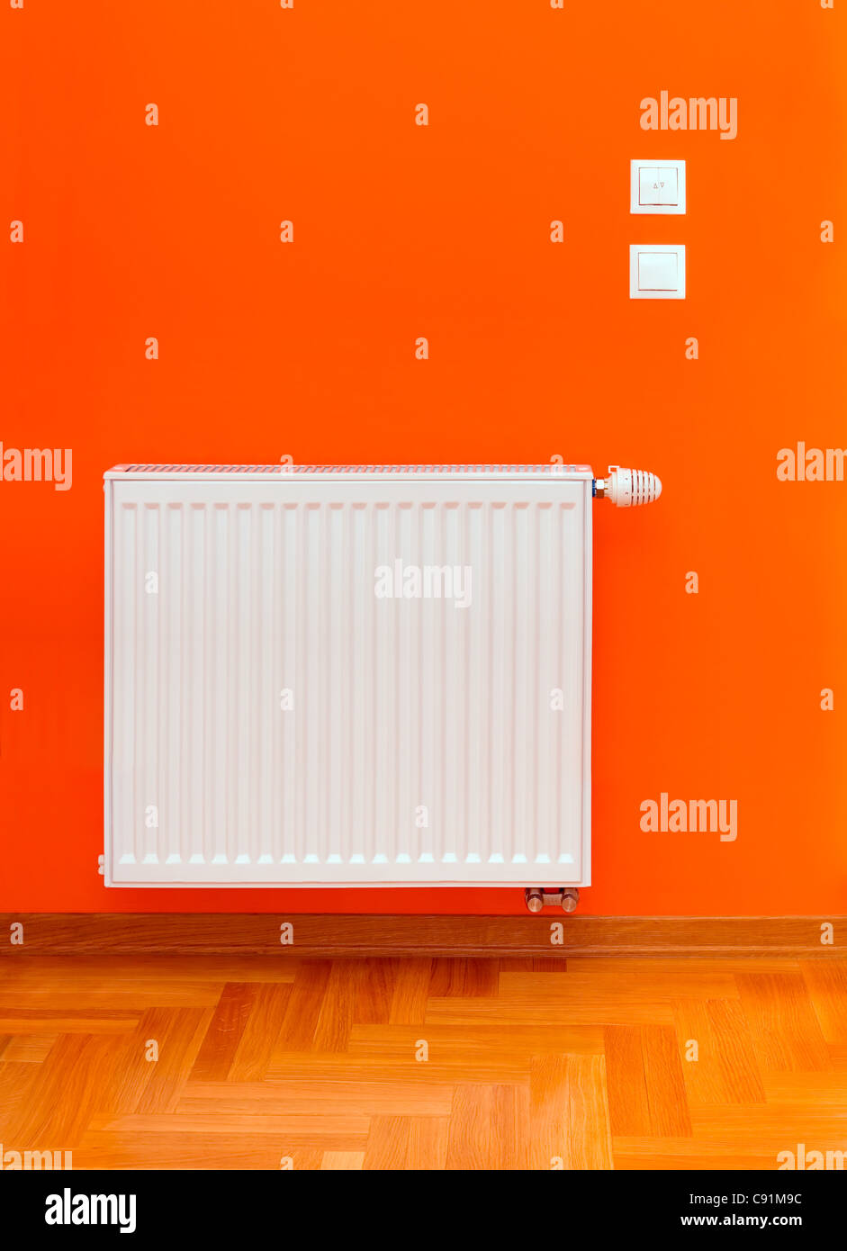 Radiator heater attached on the orange wall Stock Photo