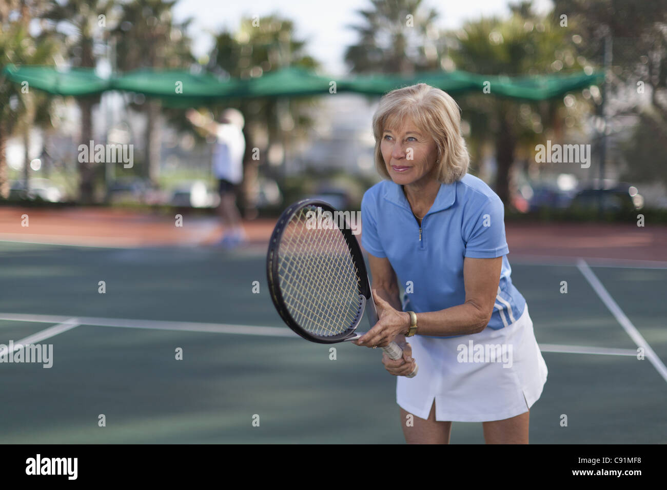 Older woman playing tennis outdoors Stock Photo