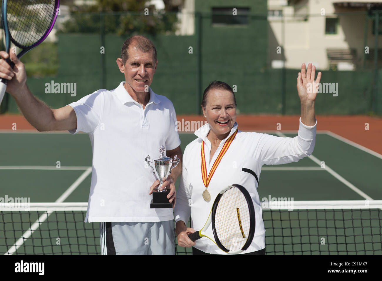 Older couple with trophy on tennis court Stock Photo