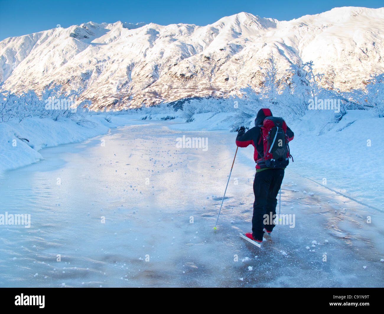 Man Nordic ice skating on the frozen Placer River, Kenai Mountains