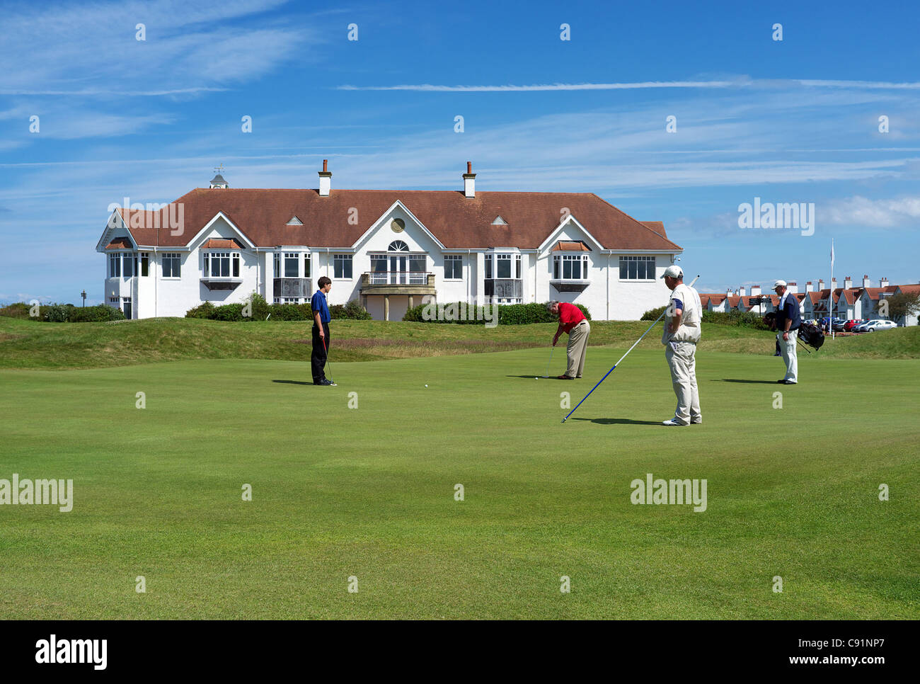 Golfers and caddies on the 18th green at the Ailsa Course, Turnberry, Ayrshire, Scotland. Clubhouse in the background. Stock Photo