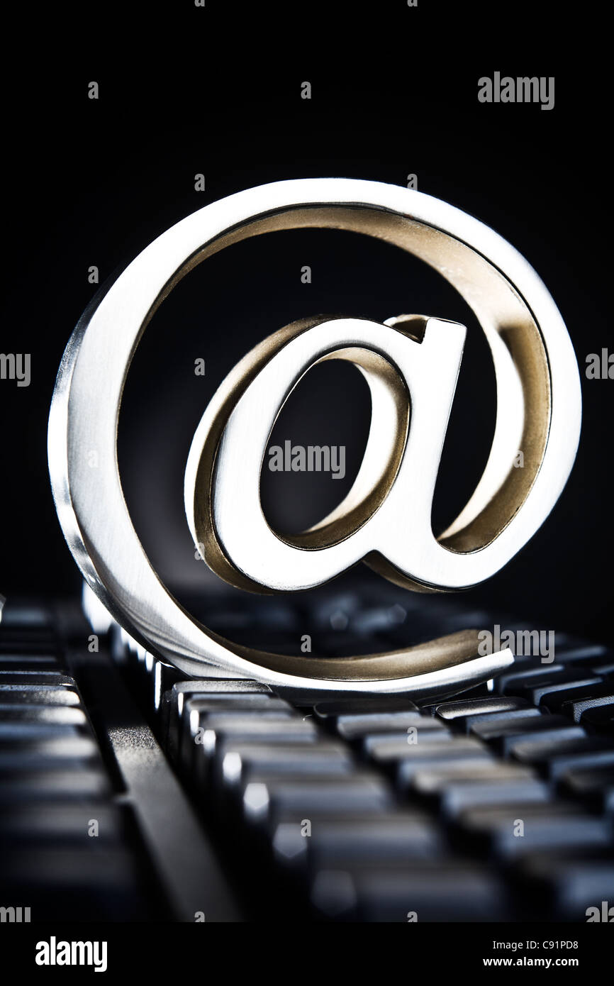 At sign, at symbol, paperweight placed on computer keyboard Stock Photo