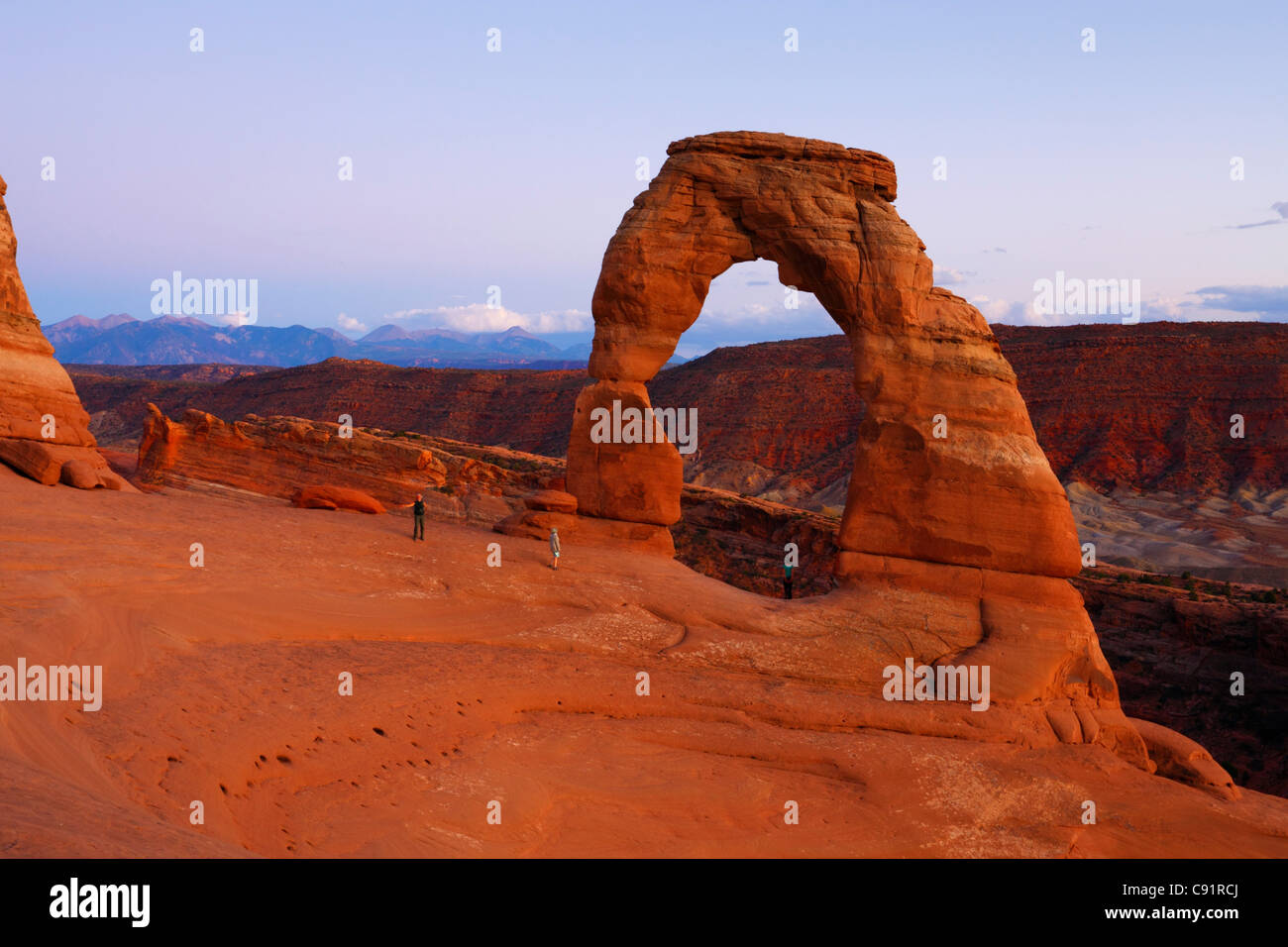 Tourists below Delicate Arch at dusk, Arches National Park Stock Photo