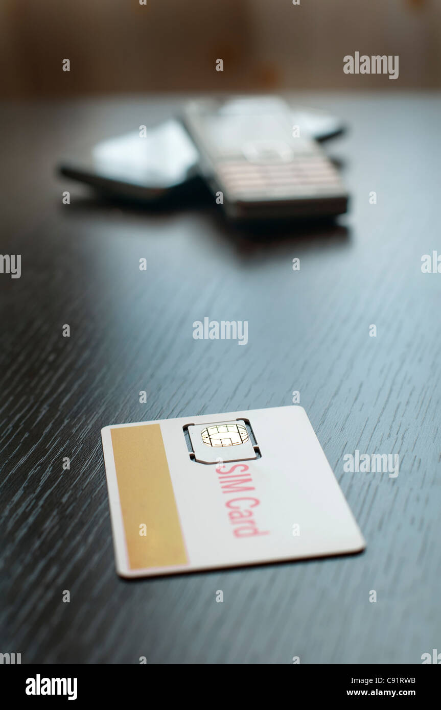 SIM card and mobile phone on table Stock Photo