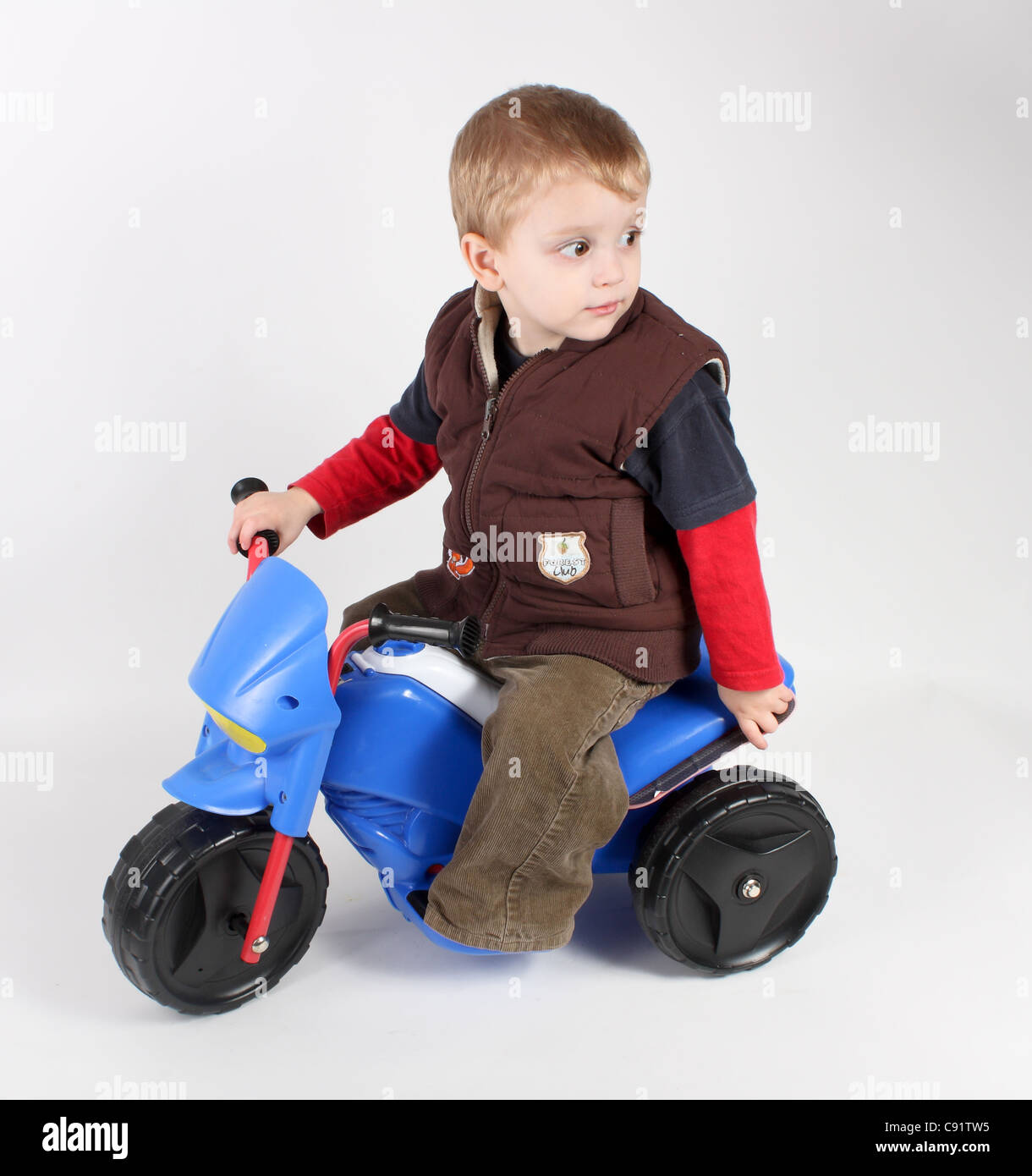A young toddler boy driving his blue electric sit on ride on motorbike