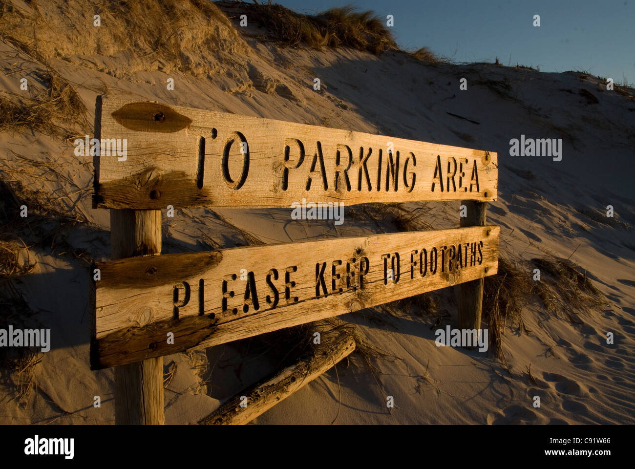 Wooden carved direction sign to parking area which is covered in sand Stock Photo