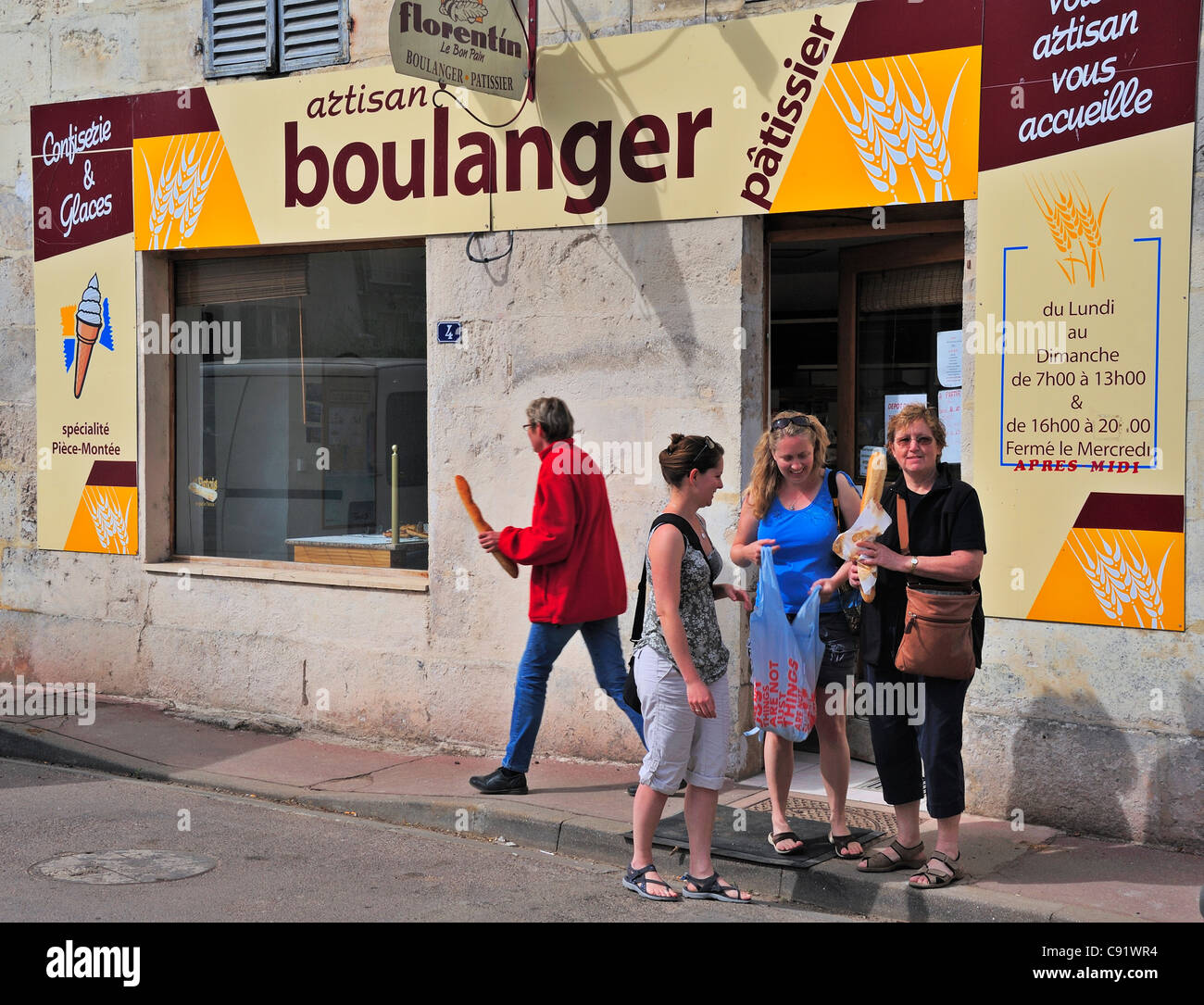 Customers coming out of a French artisanal bakery with their bread Stock Photo