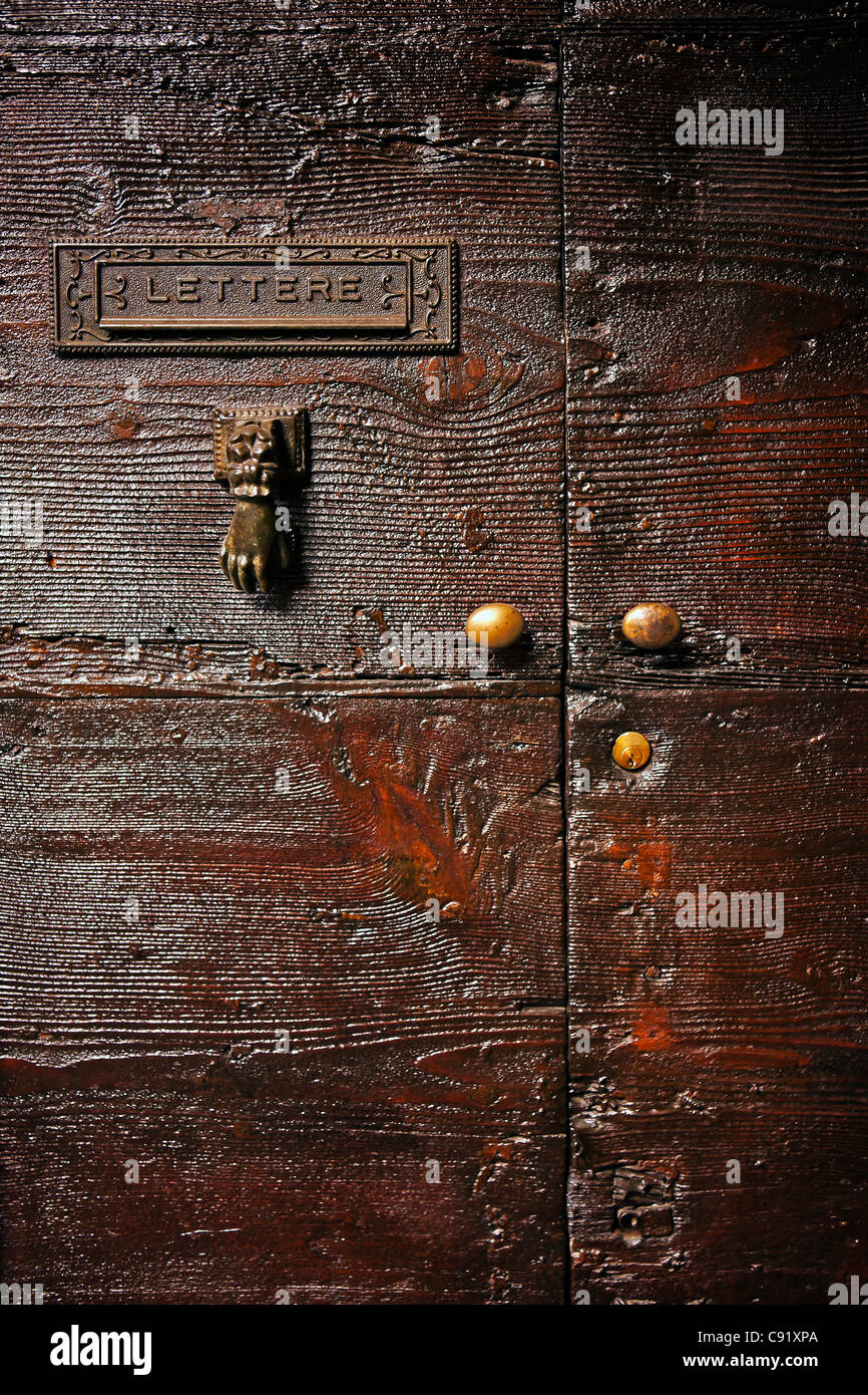 Italian wooden door with mail slot, and a door knocker Stock Photo