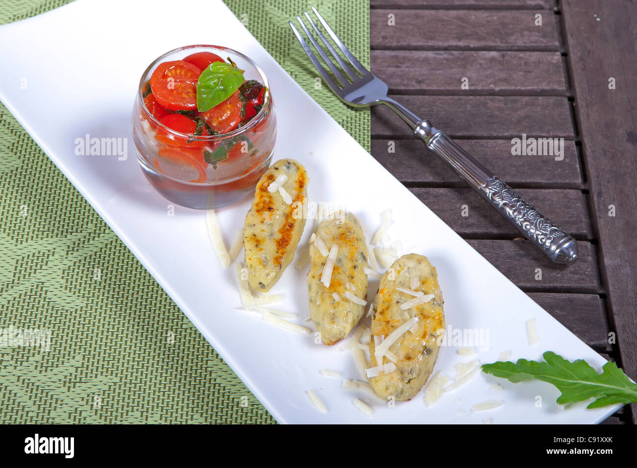Quark dumplings with roasted tomatoes, arugula as a garnish Stock Photo
