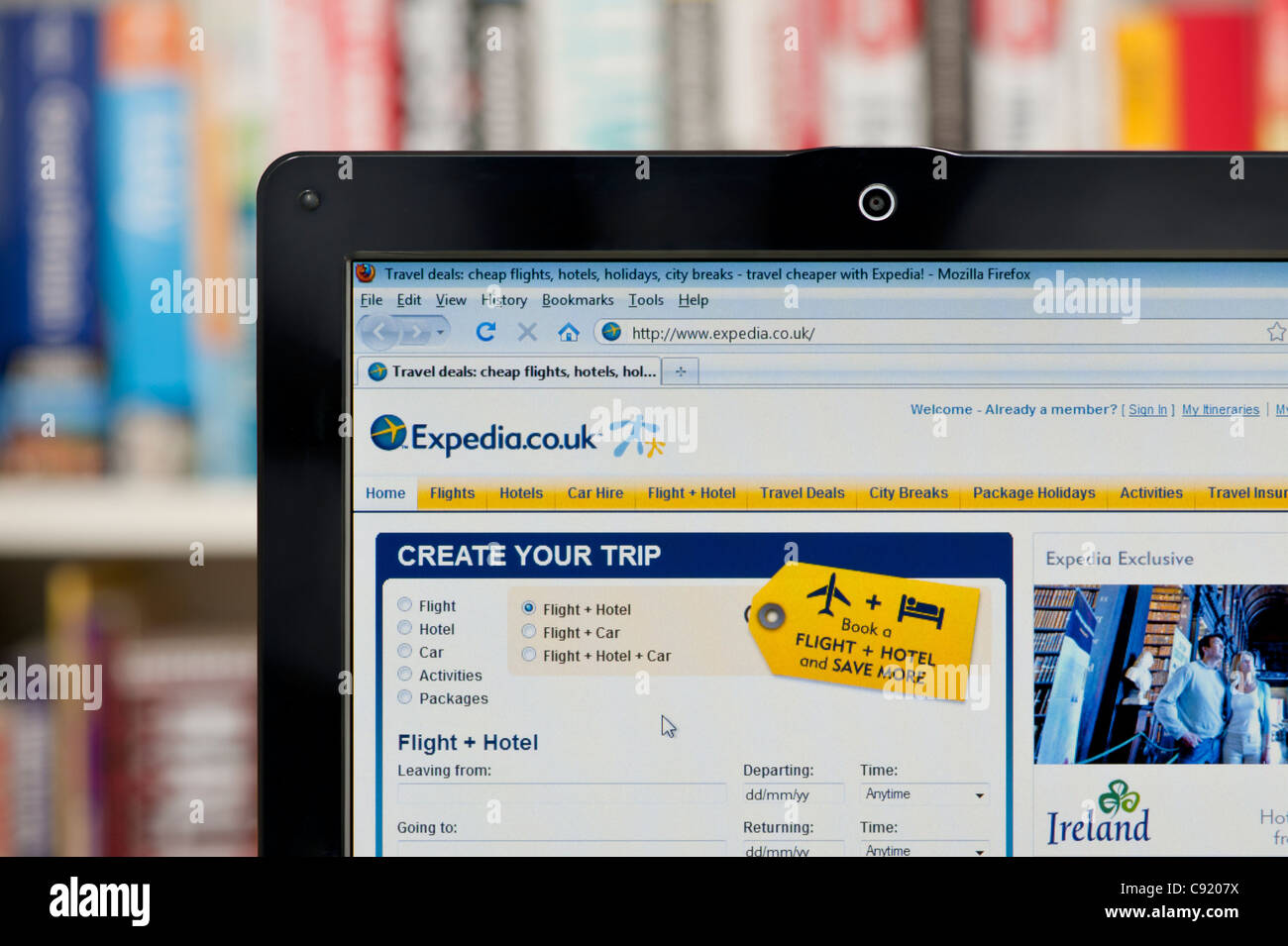 The Expedia website shot against a bookcase background (Editorial use only: print, TV, e-book and editorial website). Stock Photo
