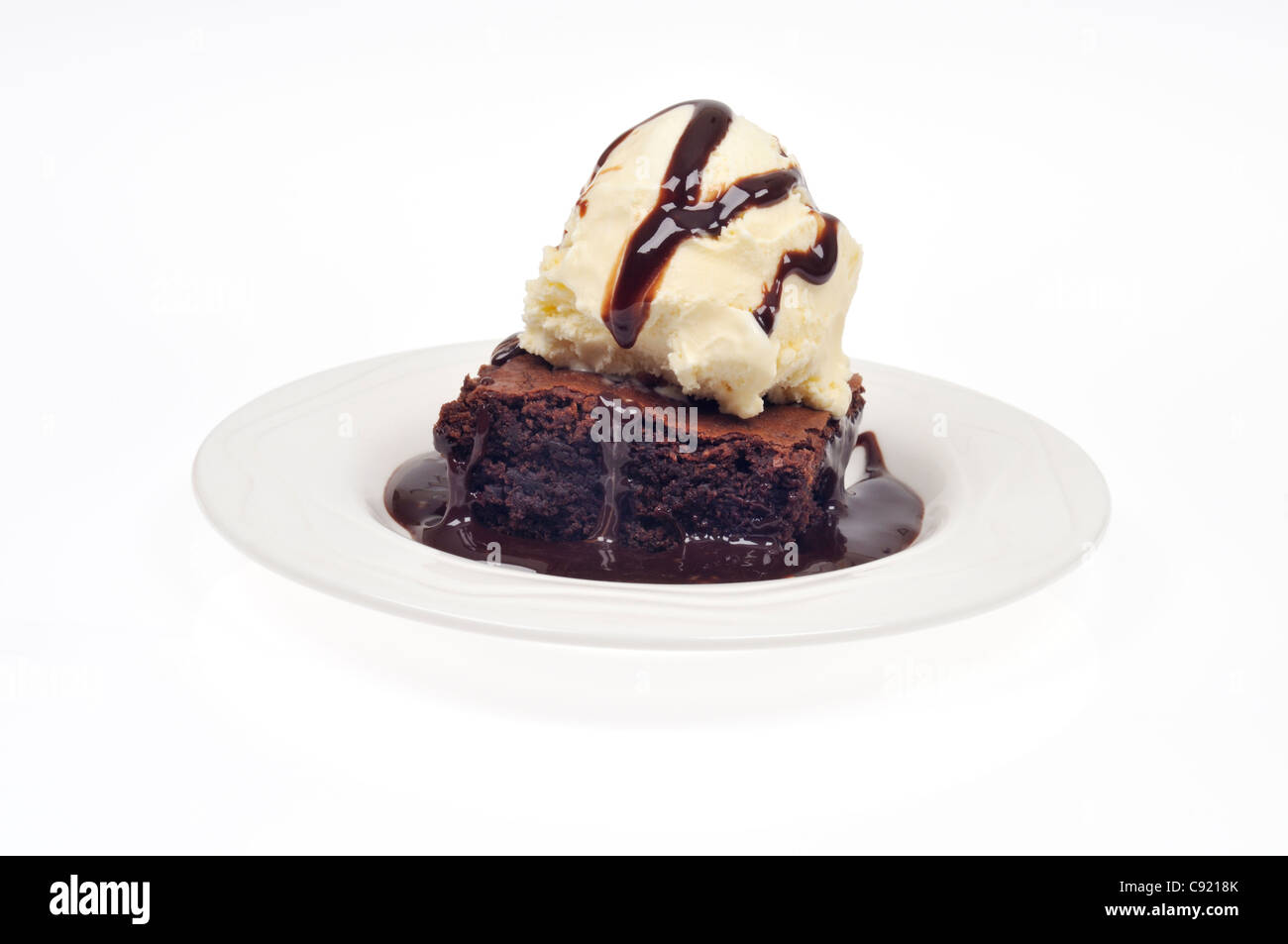Chocolate fudge brownie with vanilla ice cream and a drizzle of chocolate sauce on white background cutout Stock Photo