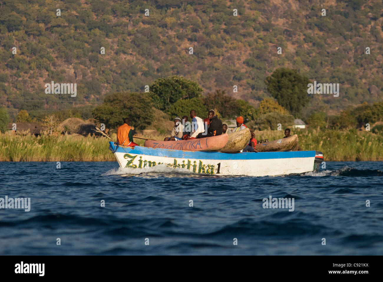 Fishermen load their canoes onto water taxis at Cape Maclear to get far out into the lake to fish. Stock Photo