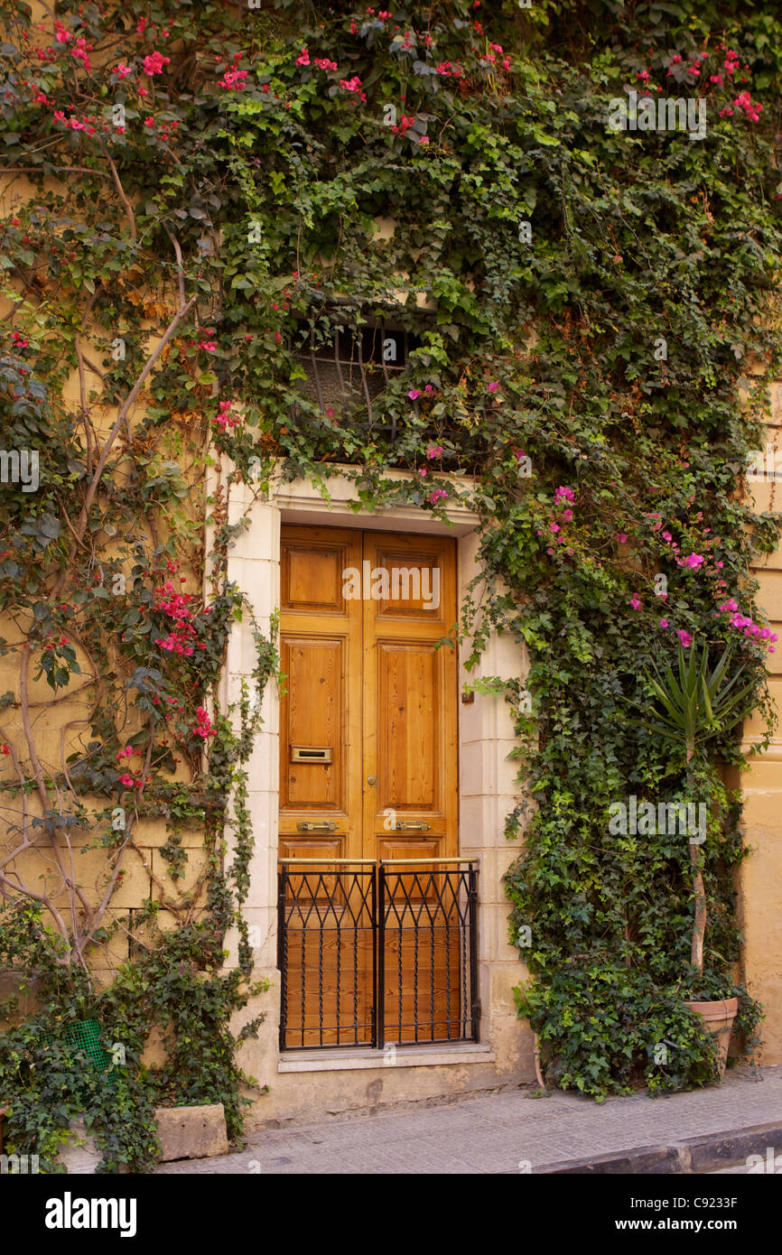 Bougainvillea covered facade of a building on a steep stretch of Merchant Street (Trik Il Merkanti), in Valletta. Stock Photo
