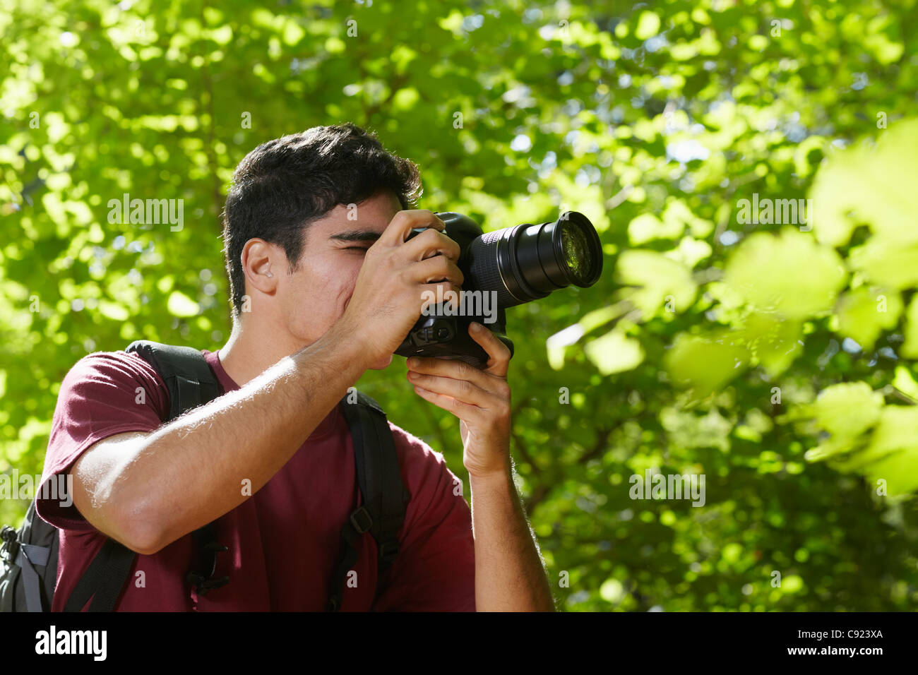 young hispanic man trekking among trees and taking pictures with dslr camera. Horizontal shape, side view, copy space Stock Photo