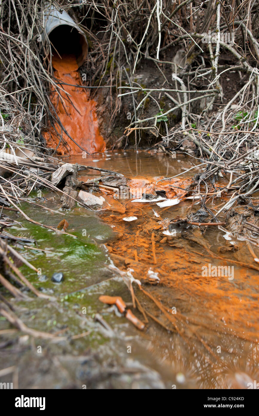 Rust colored water running through a drainage culvert, Alaska Stock Photo