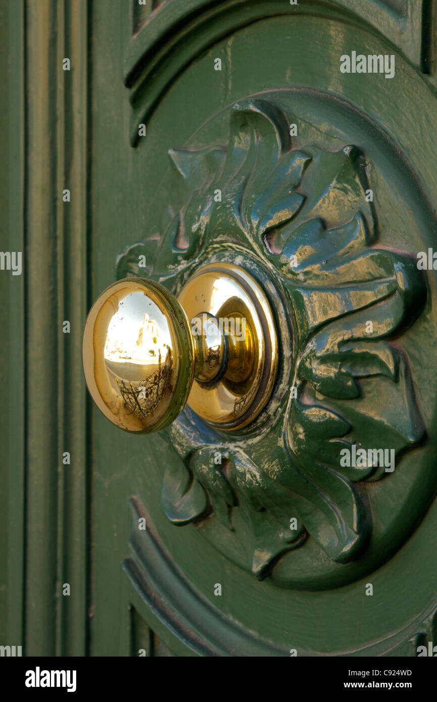 Polished brass door handle on a bottle green painted door in the town of Mosta. Stock Photo
