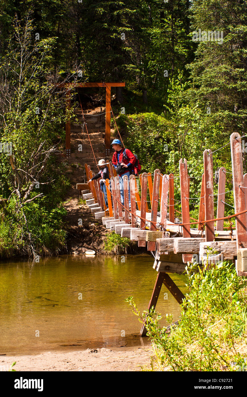 A father and son hiking across a suspension bridge that crosses Byers