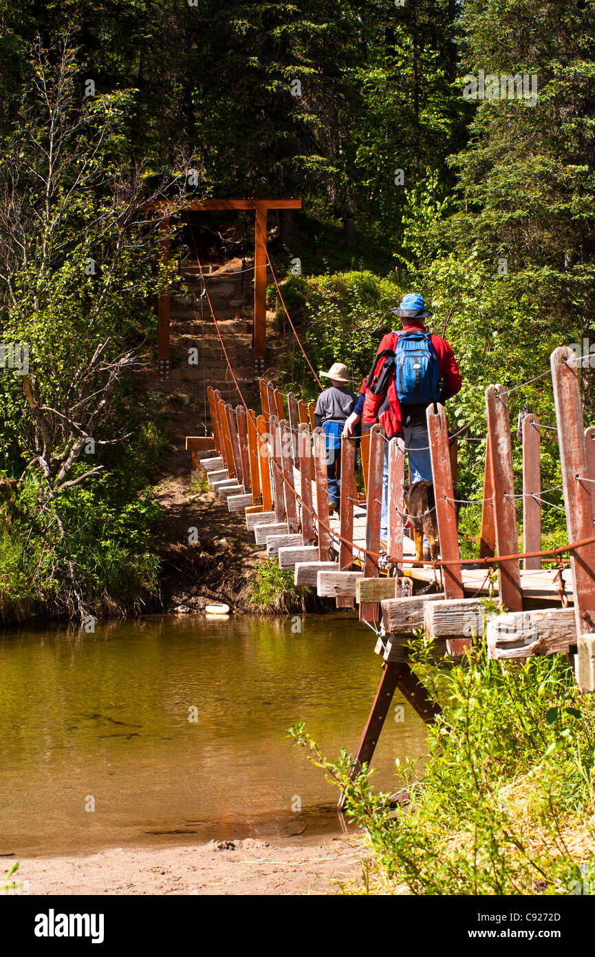 A father and son hiking across a suspension bridge that crosses Byers