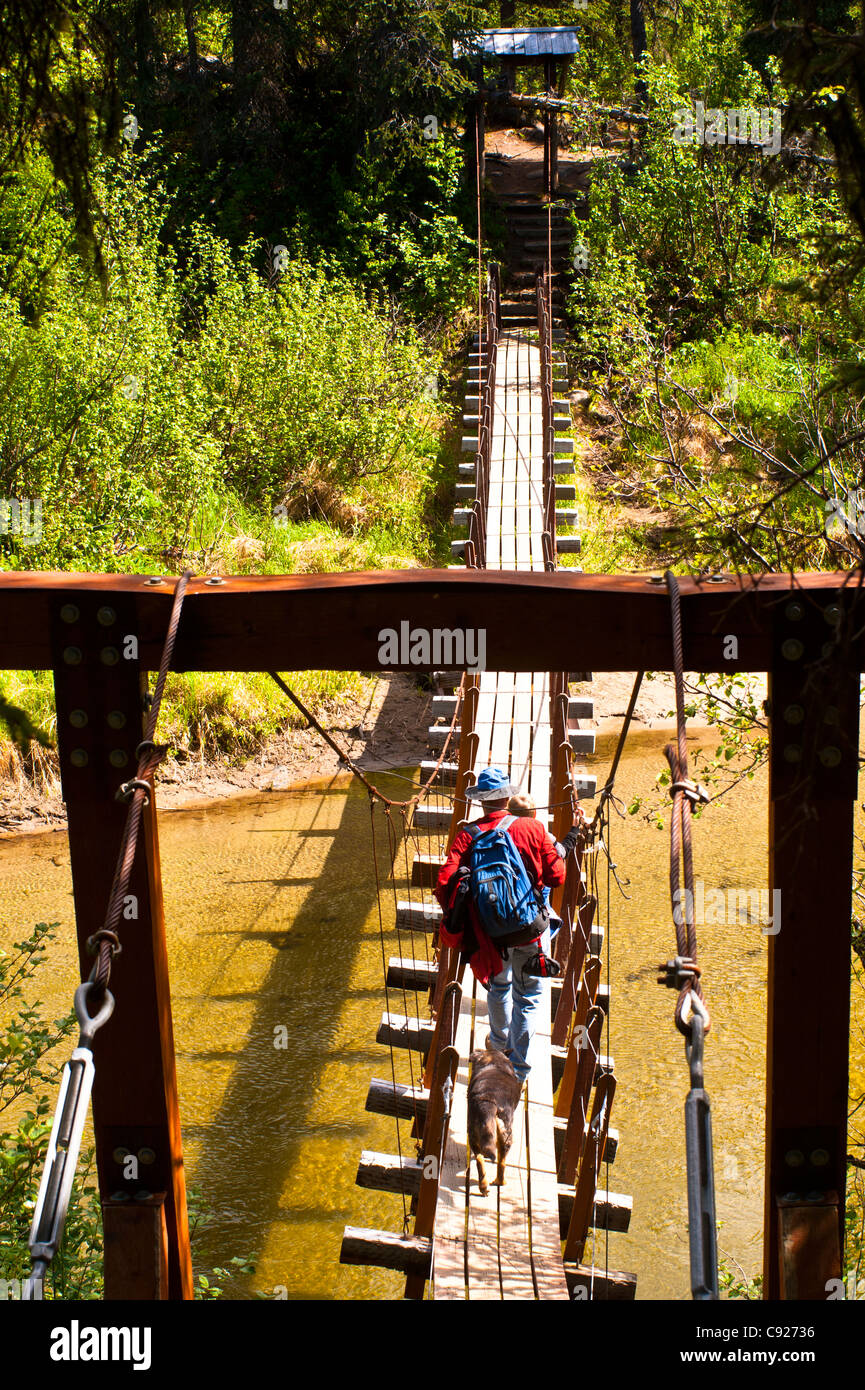 A father and son hiking across a suspension bridge that crosses Byers