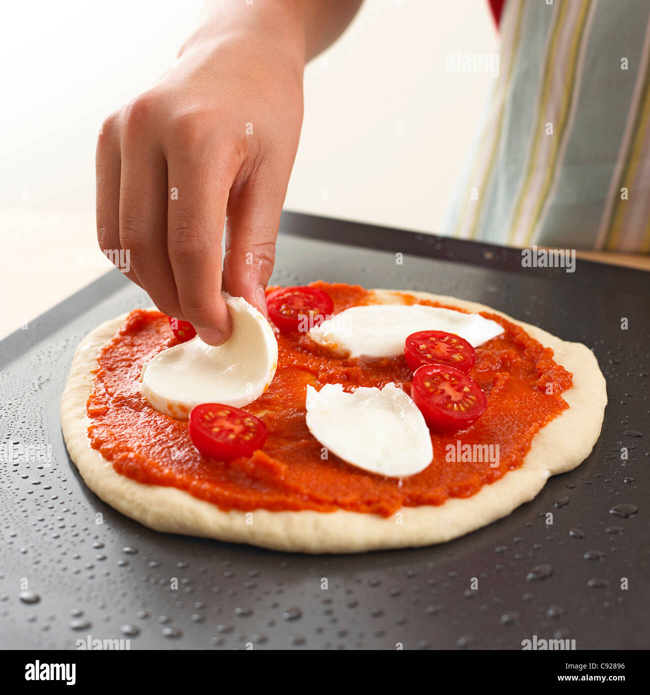 Putting mozzarella cheese on pizza base Stock Photo - Alamy