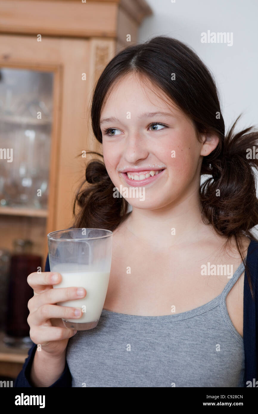 Smiling girl drinking milk in kitchen Stock Photo Alamy