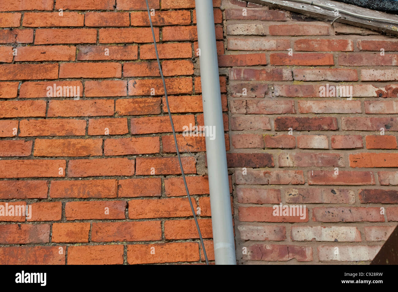 Contrast of old hand made bricks with modern machine made bricks on adjacent walls old farmhouse