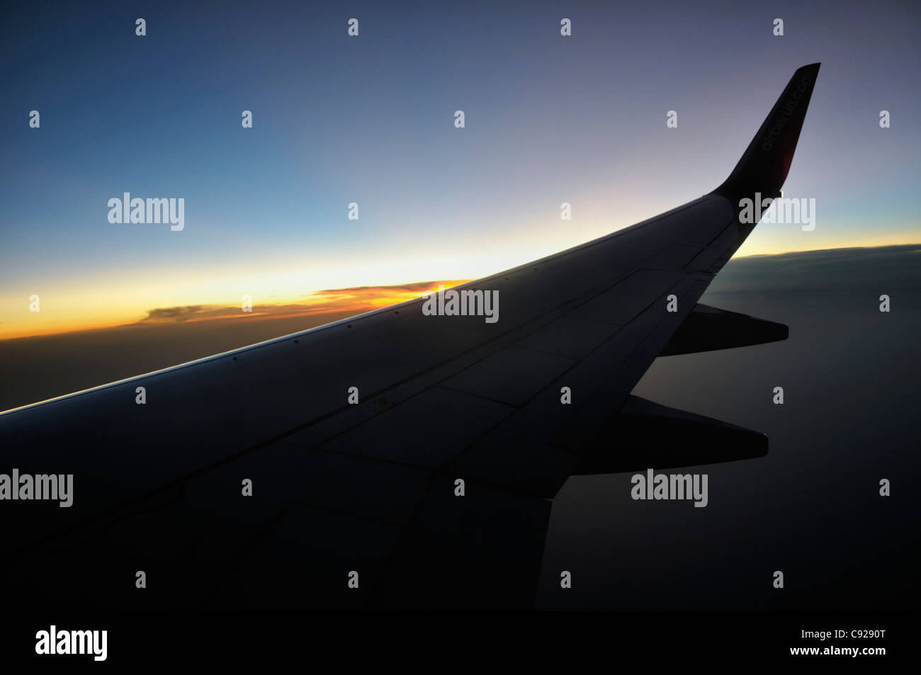 Silhouette of airplane wing with a sunset sky Stock Photo