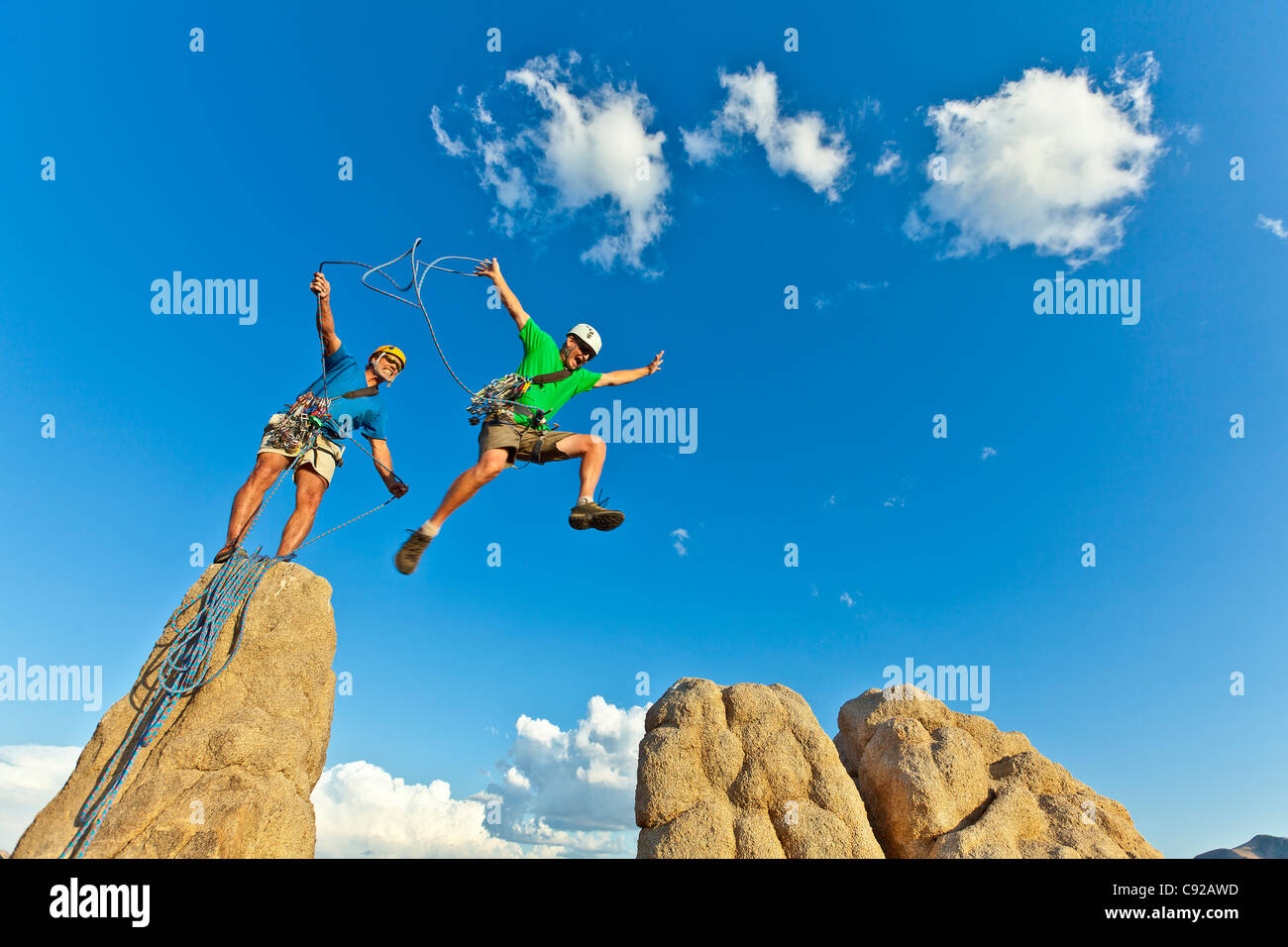 Team of climbers struggle to the summit of a rock pinnacle after a challenging ascent. Stock Photo