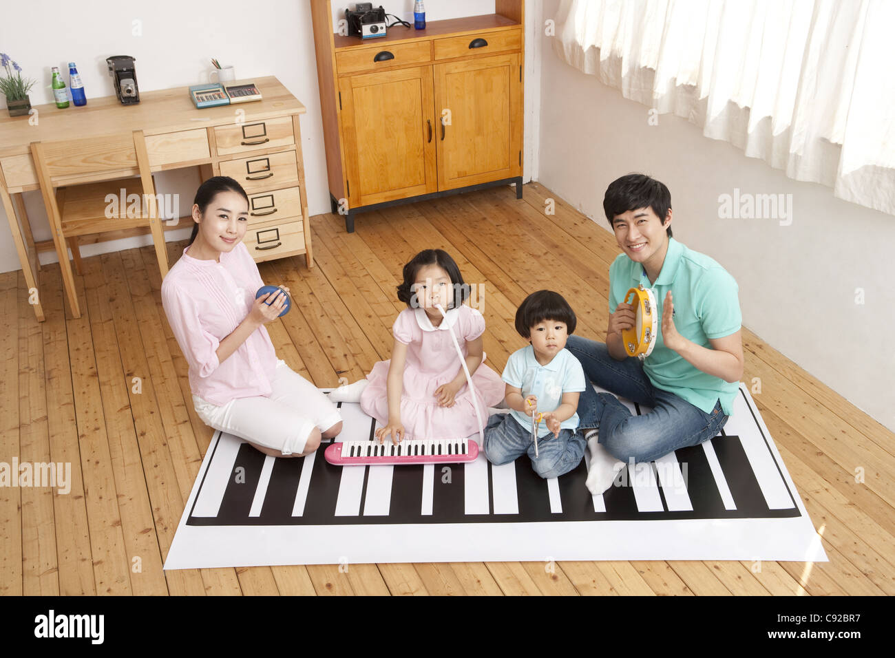 Parent With Children Sitting On Piano Painted Floor Smiling Stock