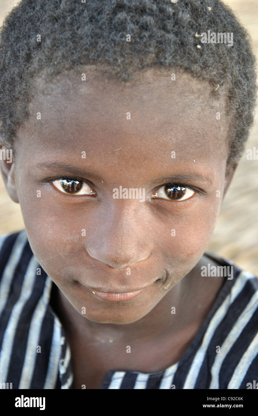 A Young Boy With Short Hair And Large Brown Eyes Striped Shirt