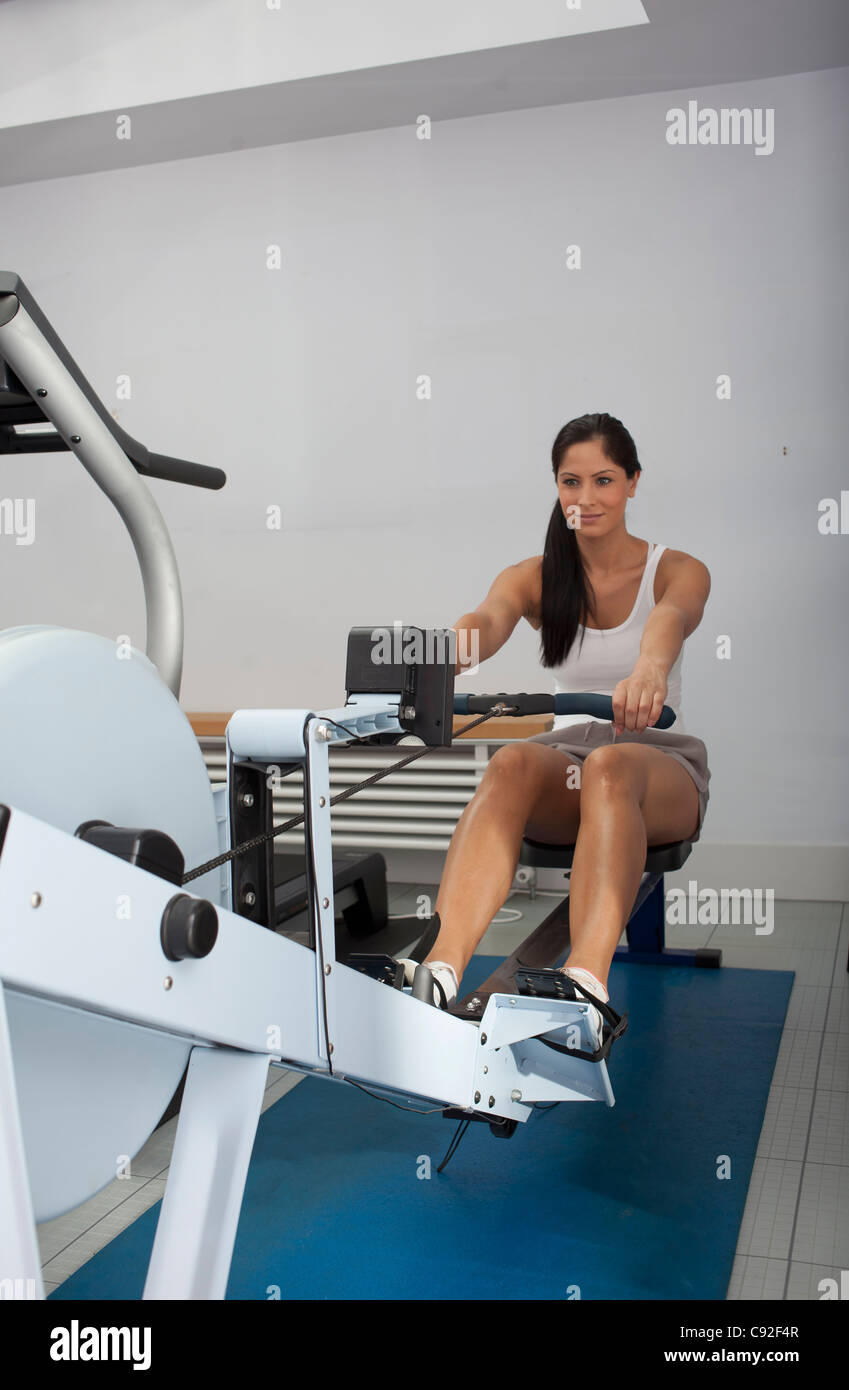 Smiling woman using rowing machine Stock Photo - Alamy