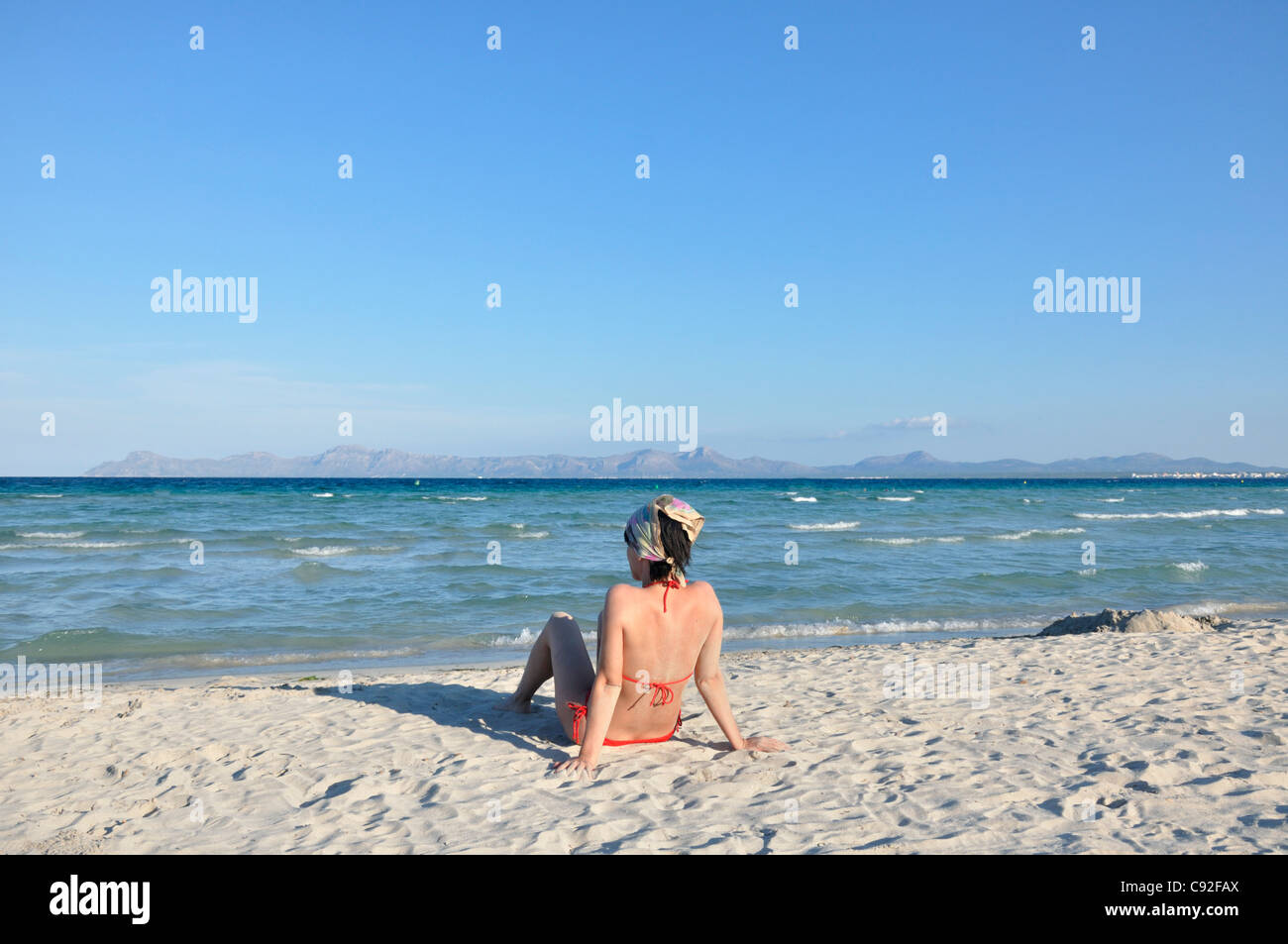Mid adult woman sitting on beach, Alcudia, Mallorca, Spain, Europe Stock Photo
