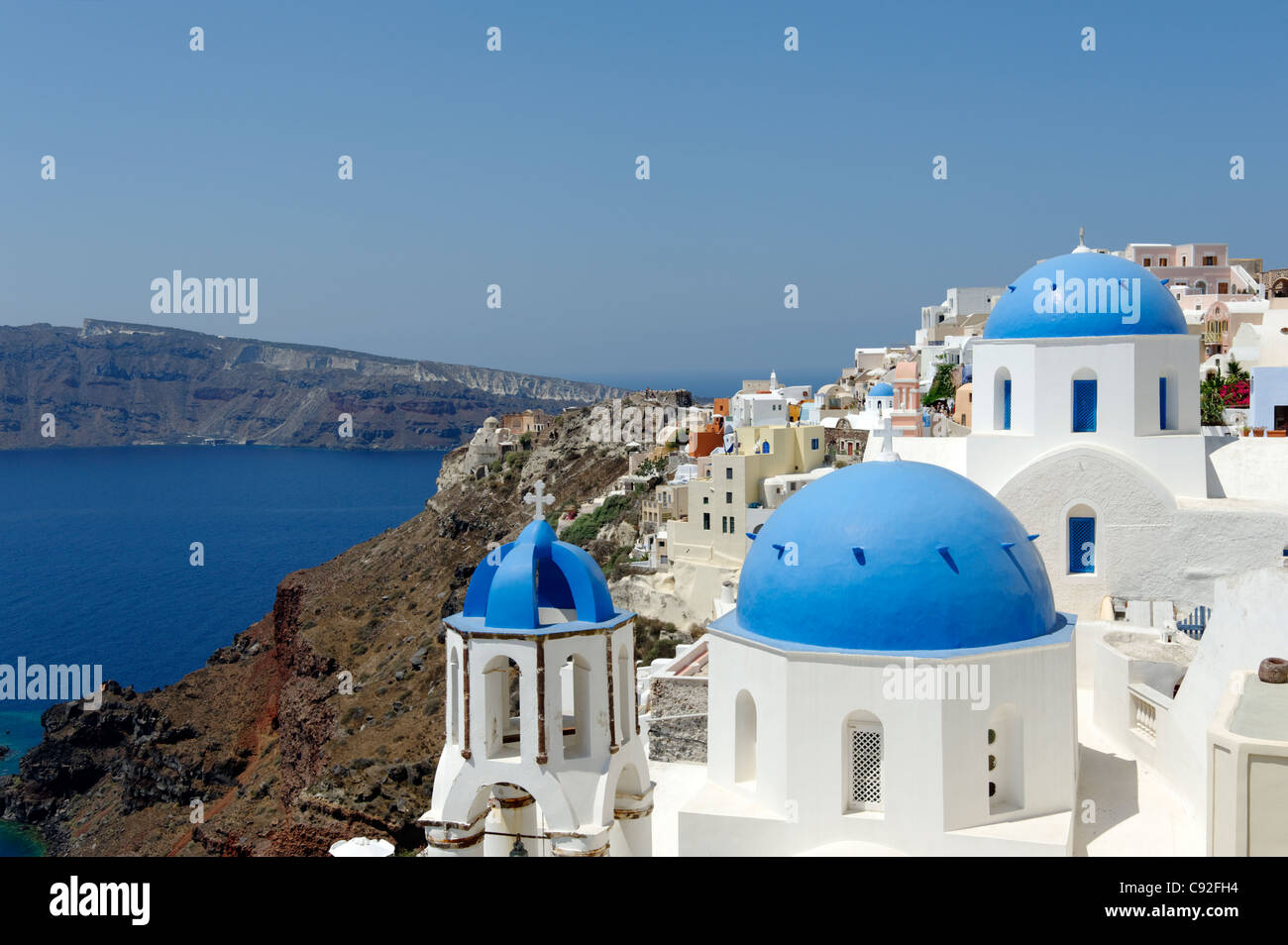 View of the picture postcard village of Oia which is a romantic mix of blue domed churches and whitewashed buildings. Santorini Stock Photo