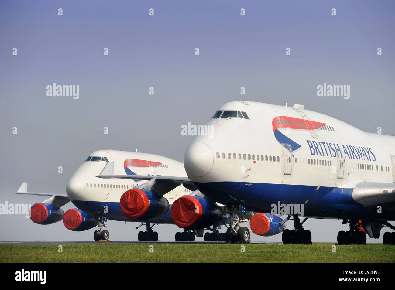 Two British Airways Boeing 747 passenger jets with engine covers parked