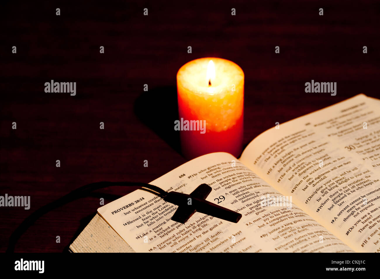 crucifix necklace on an open bible with illuminated candle stock