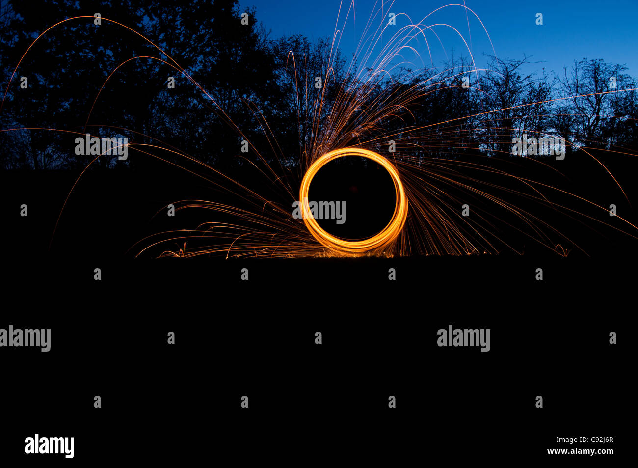 Steel wool spinning, creating gorgeous circular streaks of golden light from burning wire wool inside a whisk attached to wire, or rope. Stock Photo